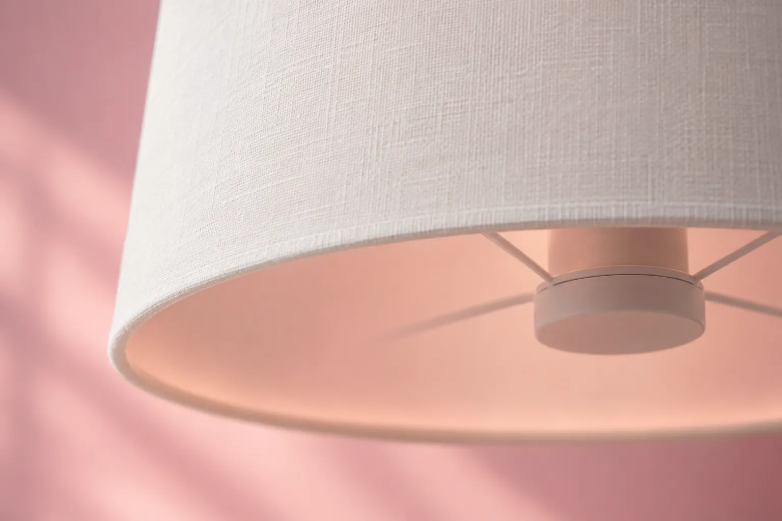 Close-up of a white lampshade rim and concealed fitting against a coral background