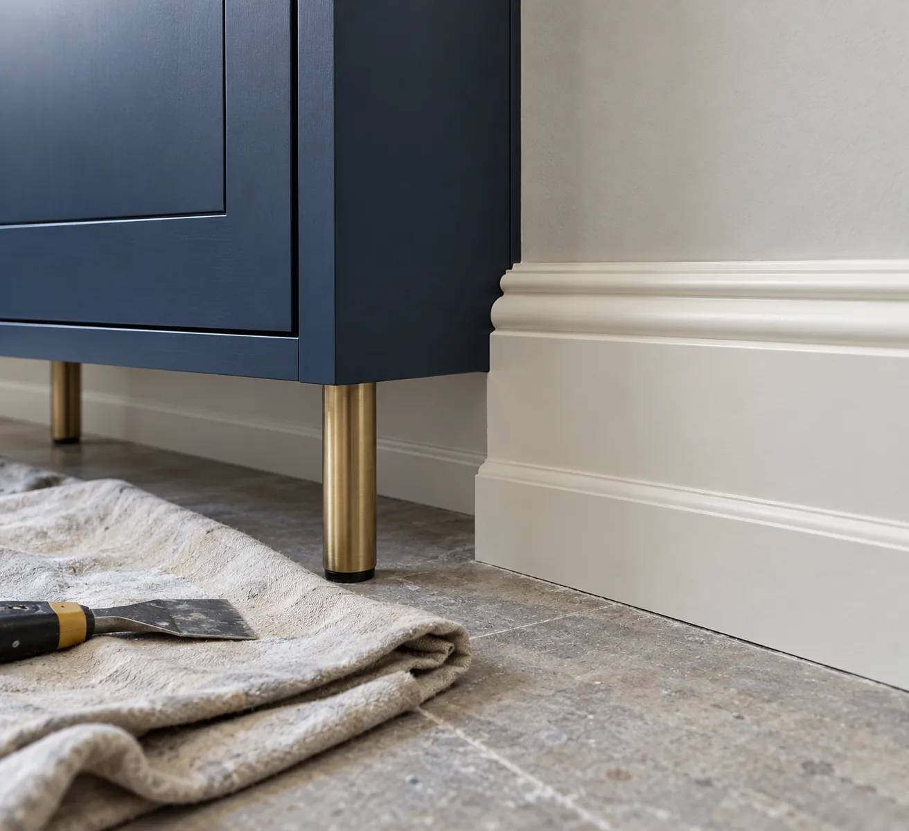 Low view of a navy cabinet beside an ivory skirting board and installation tools